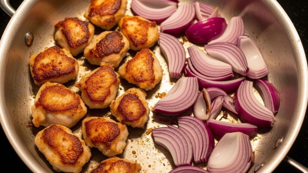 Sizzling chicken and purple onions cooking in a pan.
