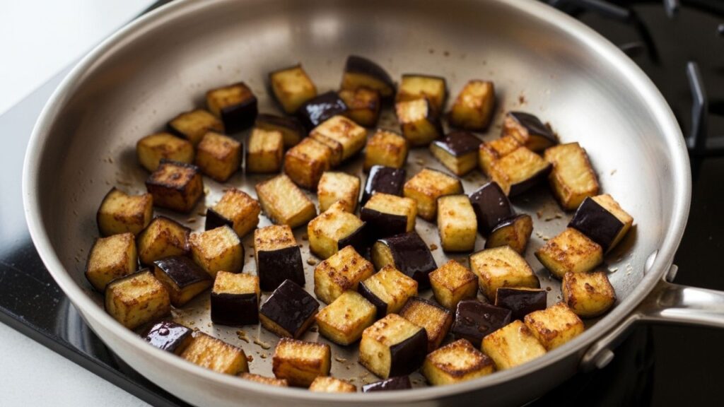 Golden brown sautéed eggplant cubes cooking in a pan for a creamy pasta sauce.