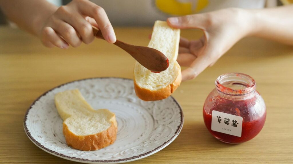 Spreading spicy remoulade on French bread as a base for a Shrimp Po’ Boy.