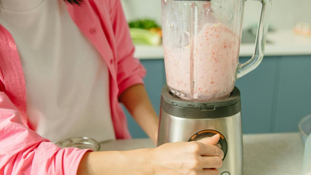 High-speed blender mixing pink strawberries and cream into a smooth frappe.